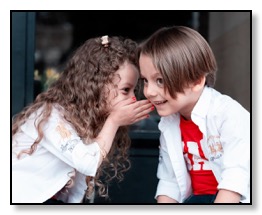 Little girl whispering to a little boy